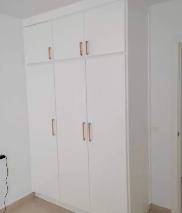 Armario blanco a medida con puertas y cajones.